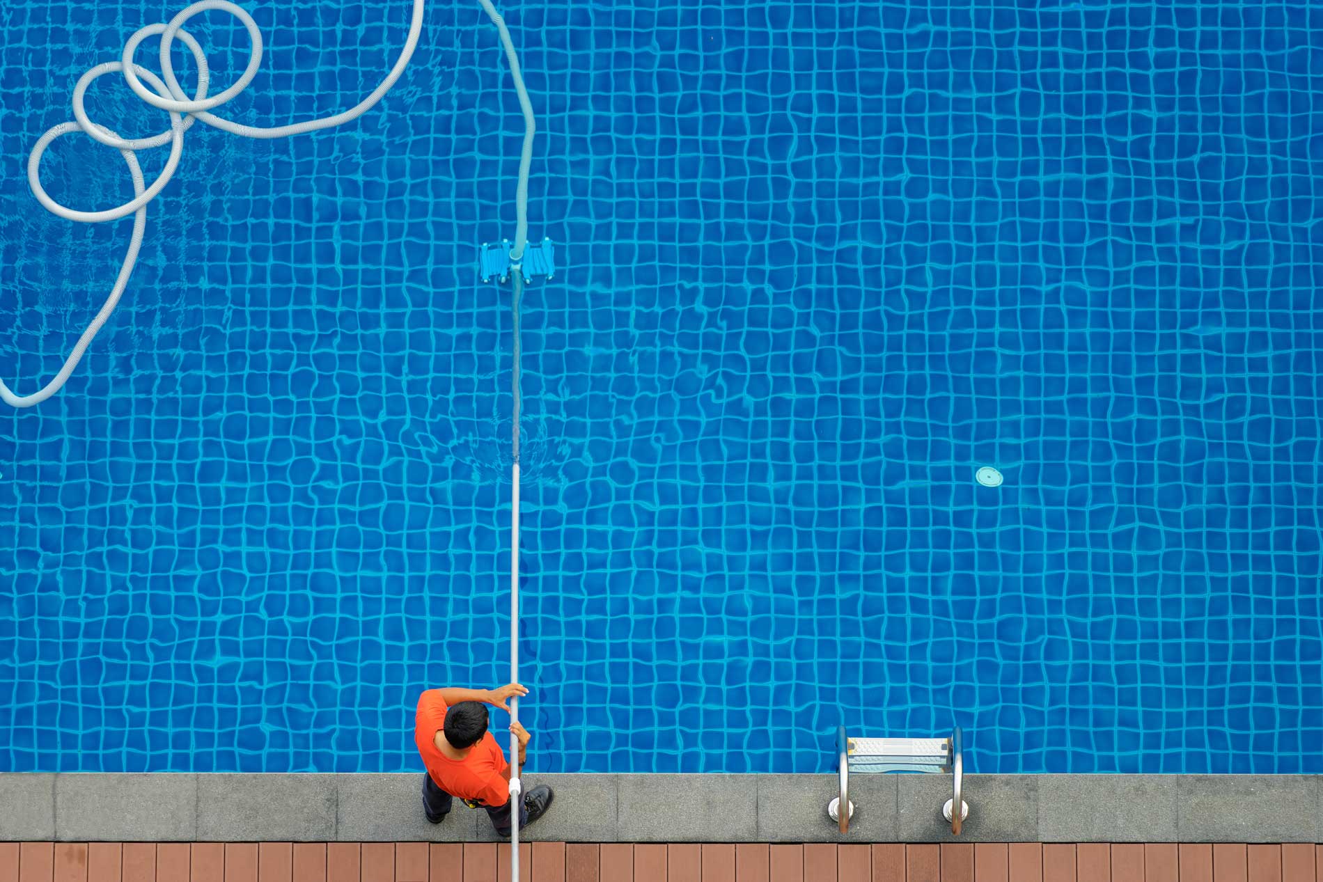 A pool repair worker is cleaning a blue pool
